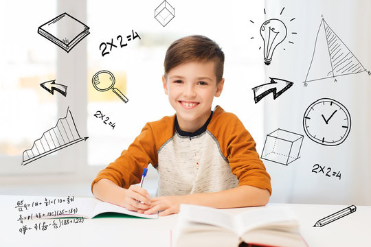 smiling student boy writing to notebook at home