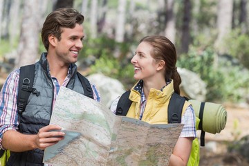 Happy couple looking face to face while holding map