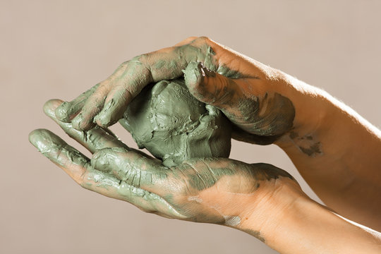 hands of a potter with blue clay