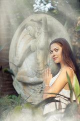 Fototapeta na wymiar Young woman is doing yoga on the ancient statue background.