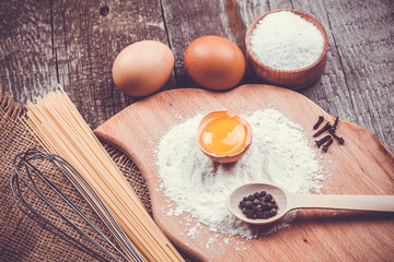 Fototapeta na wymiar Pasta spaghetti with flour, egg on old wooden background