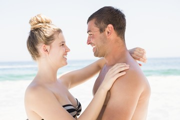 Fototapeta premium Smiling couple embracing on the beach