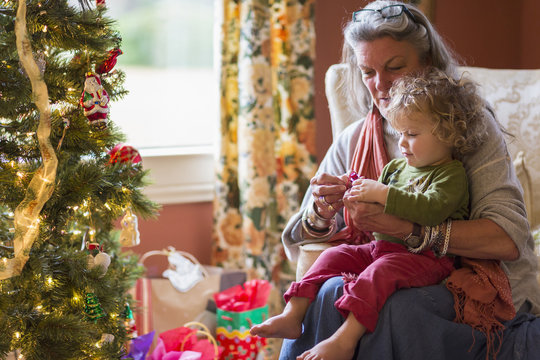 Caucasian grandmother and grandson opening presents near Christmas tree