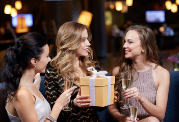 happy women with champagne and gift at night club