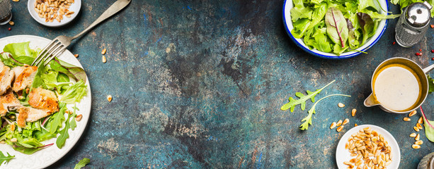 Healthy lunch eating with Chicken salad , pine nuts and oil dressing. Chicken salad with green leaves served on rustic background, top view, place for text, banner