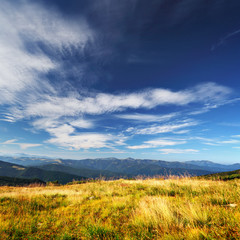 clouds over mountains and yellow grass