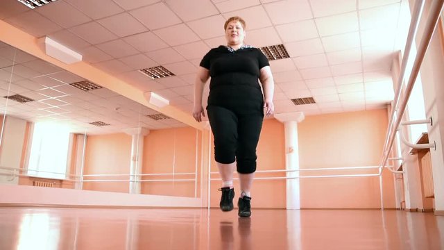 fat girl is engaged in dances in the hall. cheerful plump, gymnastics and dance