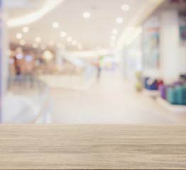 wooden table top with blur image of shopping mall interior with bokeh as background