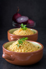 Couscous with vegetables on black stone
