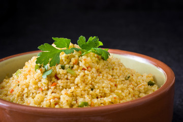 Couscous with vegetables on black stone
