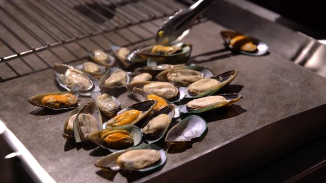 Chefs prepare clams in a restaurant in the open air in the evening.