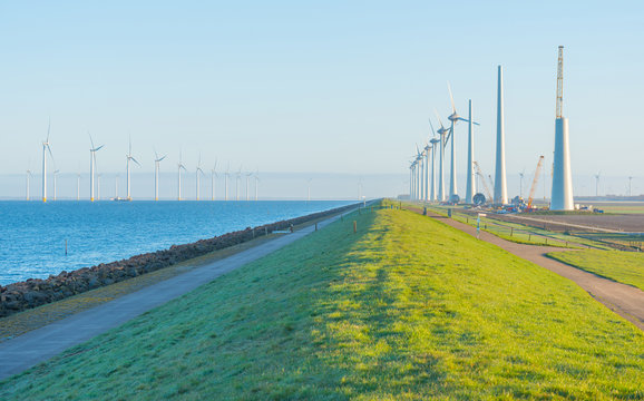 Wind turbines under construction along a dike