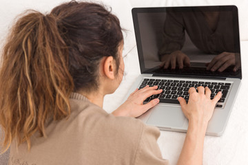 Woman working on her laptop laying on the couch