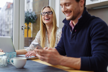 lachendes paar sitzt am tisch mit laptop und handy