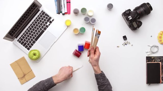 Photographer prepares his desk for work surrounded by a lot of things. Upview