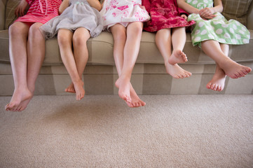 Girls sitting together in a row on sofa