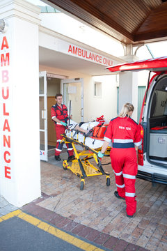 Paramedics moving patient through hospital doorway