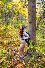 The girl tourist with backpack is in a pine forest
