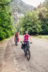 Fototapeta premium happy couple goes on a mountain asphalt road in the woods on bik