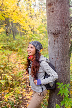 The girl tourist with backpack is in a pine forest