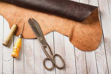 Leathersmith's work desk . Pieces of hide and leather working tools on a work table.