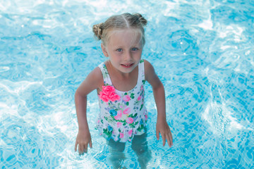 Fototapeta na wymiar Beautiful cheerful girl with two tails on the head in the pool 