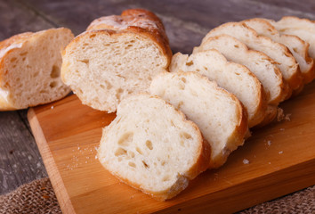 Fresh sliced bread on wooden board on burlap in rustic style