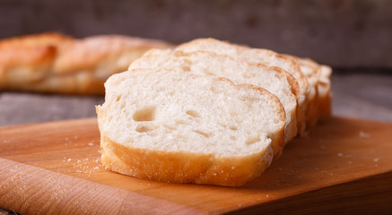 Freshly baked French baguette, sliced on a wooden board. In rustic style on sackcloth.