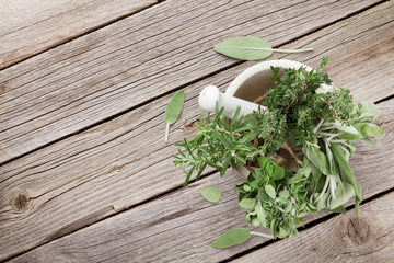 Fresh garden herbs in mortar on wooden table © evgeeenius