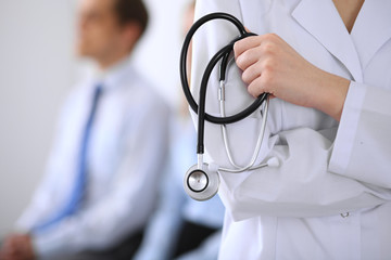 Doctor holding a stethoscope in his hands , the patient on the background