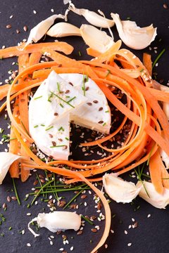 Top view on portion of camembert with garlic and carrot