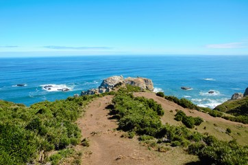 Coastal view onto the Muelle de las Almas with a clear blue sky and green hills