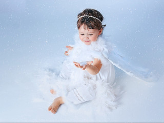 Little girl with angel wings playing with snowflakes