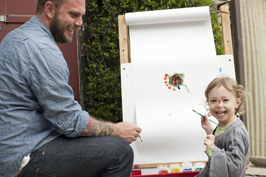 Father fooling around putting paint on daughter's face