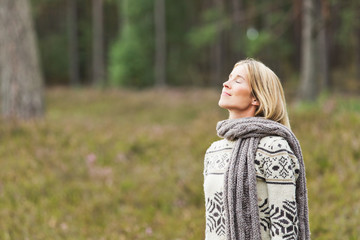 Mid adult woman wearing sweater with eyes closed