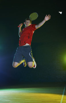 Young male badminton player mid air on court