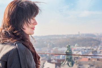 Girl brunette in a gray coat with a brown scarf on the roof of the Town Hall of Lviv