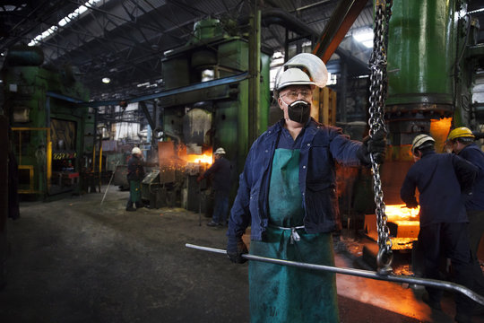 Operative prepares to hook steel billet out of furnace