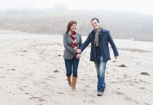 Couple walking on beach, Thurlestone, Devon, UK