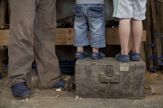 Father with sons standing on tool box in boat  workshop