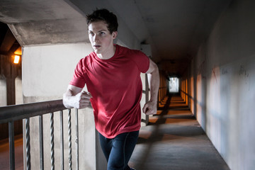 Young man running on city bridge