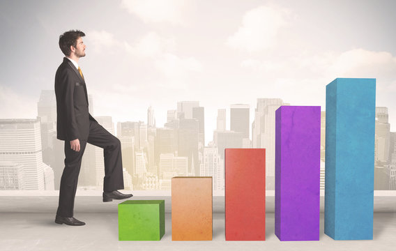 Business person climbing up on colourful chart pillars concept
