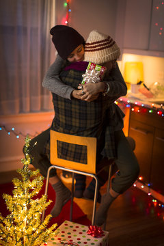 Young couple hugging on chair at christmas
