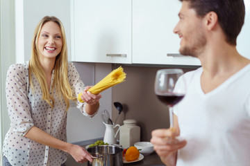 lachende frau hält spaghetti in der hand und zeigt auf ihren freund