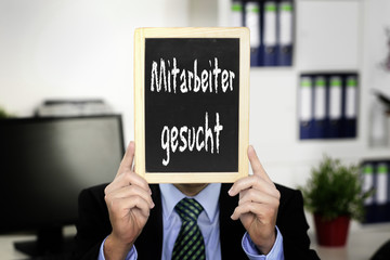 Mann im Anzug hält Werbetafel Mitarbeiter gesucht