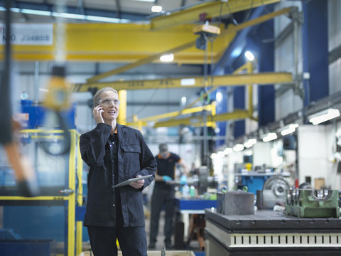 Female Worker Using Mobile Phone In Engineering Factory