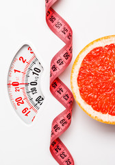 Grapefruit with measuring tape on weight scale. Dieting