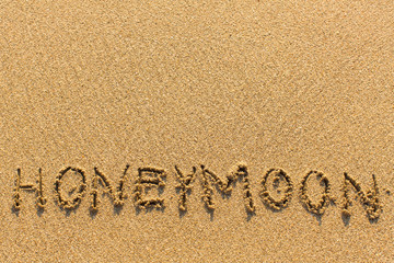 Honeymoon - written manually on the texture of sea sand.