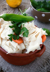 Raw Tripe with Vegetables and Seasoning in a Rustic Ceramic Bowl on a Wooden Background 