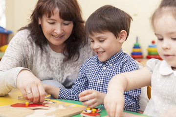 beautiful caucasian teacher collects the puzzle with a pupil